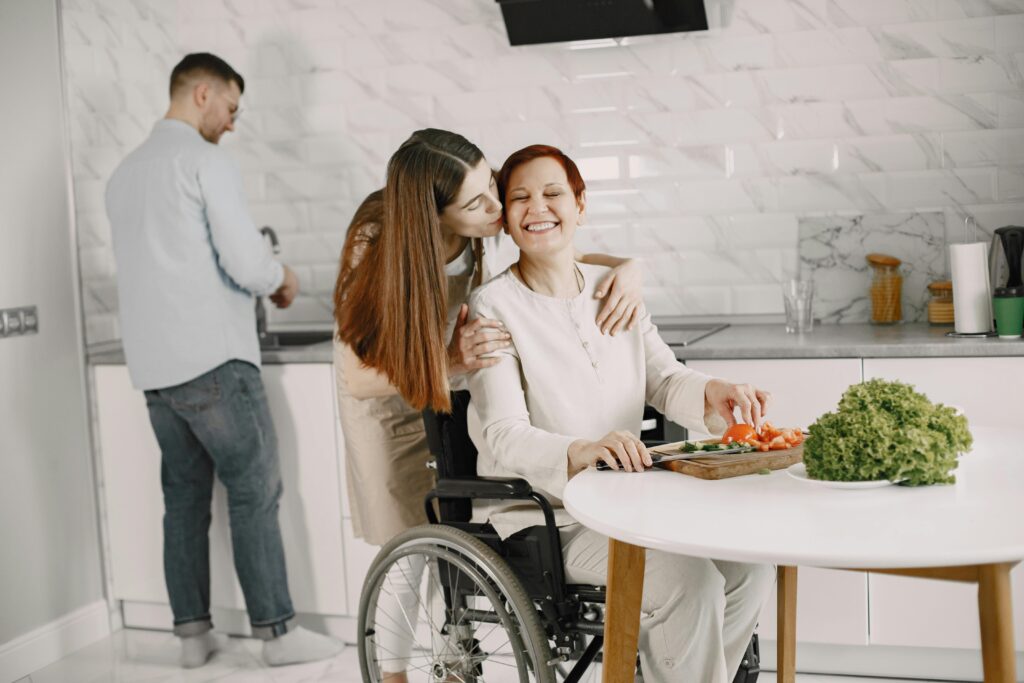 A heartwarming scene of family bonding in the kitchen, featuring a woman in a wheelchair being affectionately embraced.